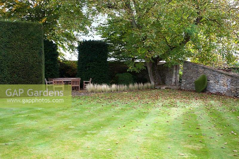 Secluded seating area beside lawn. Radcot House, Oxfordshire, UK