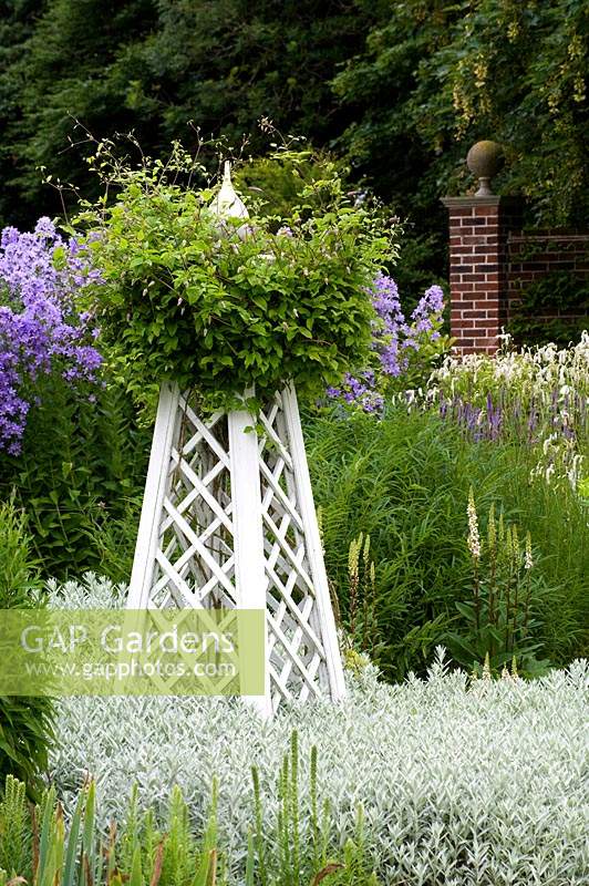 White obelisk with clematis in mixed blue and white themed border