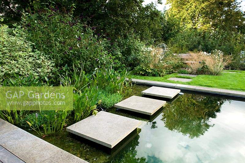 Paving slabs as stepping stones over modern pond - natural swimming pool