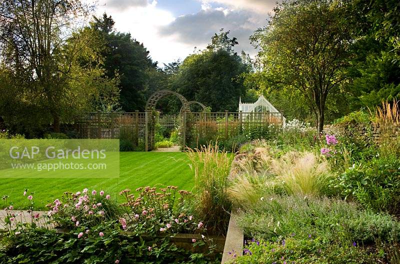 Raised borders and central lawn in modern country garden