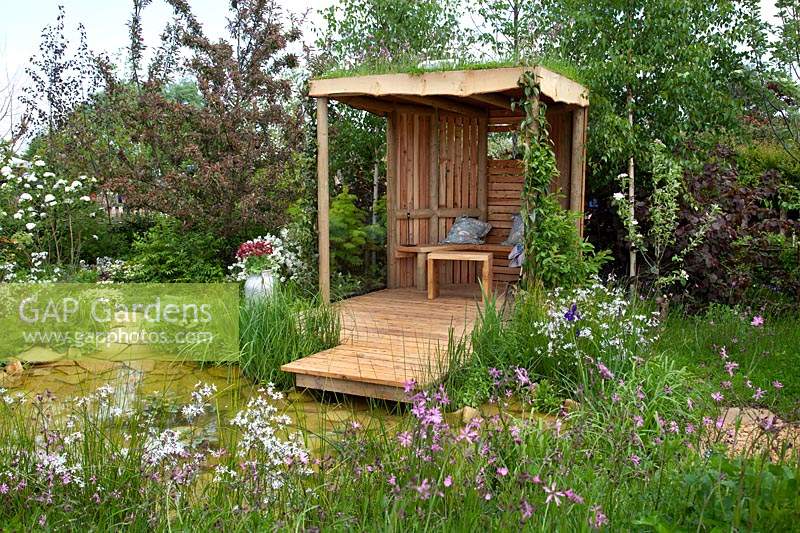 The garden shelter, next to the dew pond, surrounded by wildflowers in 'Garden Inspiration: The Dew Pond' at RHS Malvern Spring Festival 2018