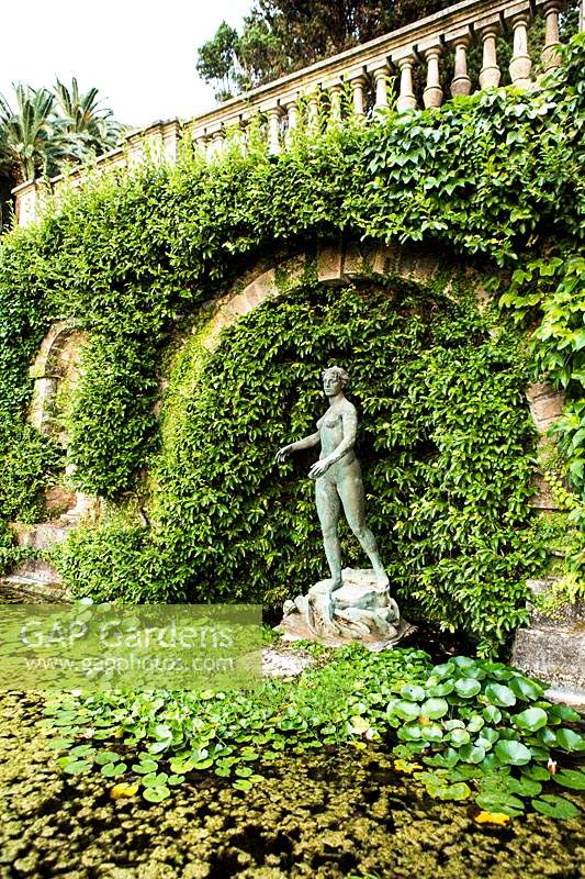 Figurative statue in an arch at the back of a pond