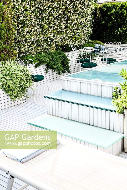 Modern terrace garden with swimming pool and sun loungers. 