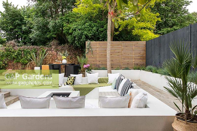 Sunken seating surrounded with wooden decking in modern garden.