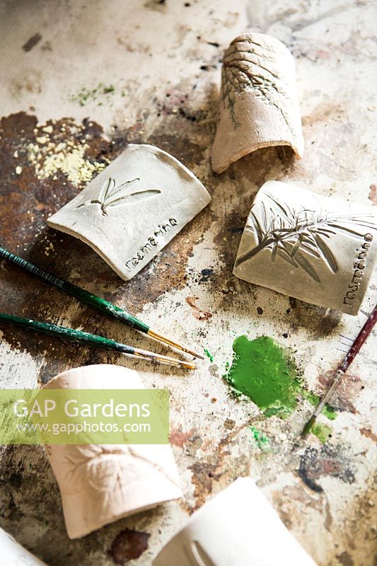 Fine paintbrushes and paint for adding colour to the impressions on ceramic plant labels