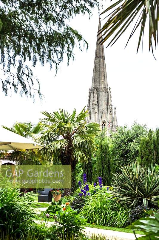Roof garden, view of tropical beds with palms and conifers, to church steeple beyond