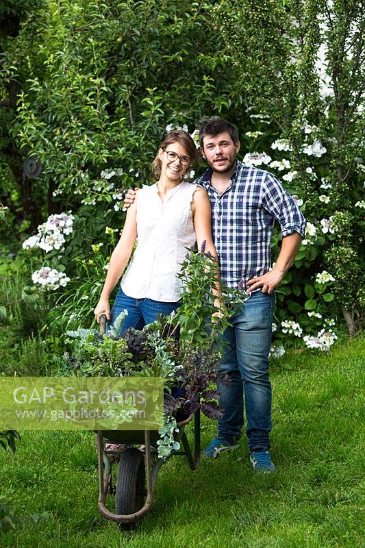Couple standing with wheelbarrow of plants 