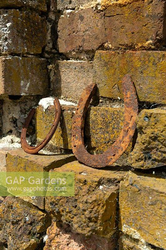 A pair of rusty 'lucky', horseshoes on a brick ledge of an old renovated bakery garden studio.
