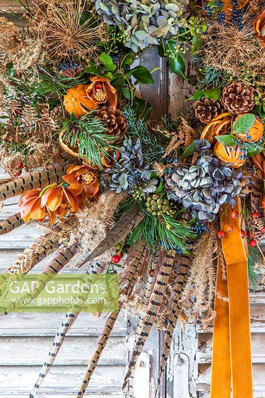 Rustic orange, green and blue festive wreath hung on vintage wooden shutters
