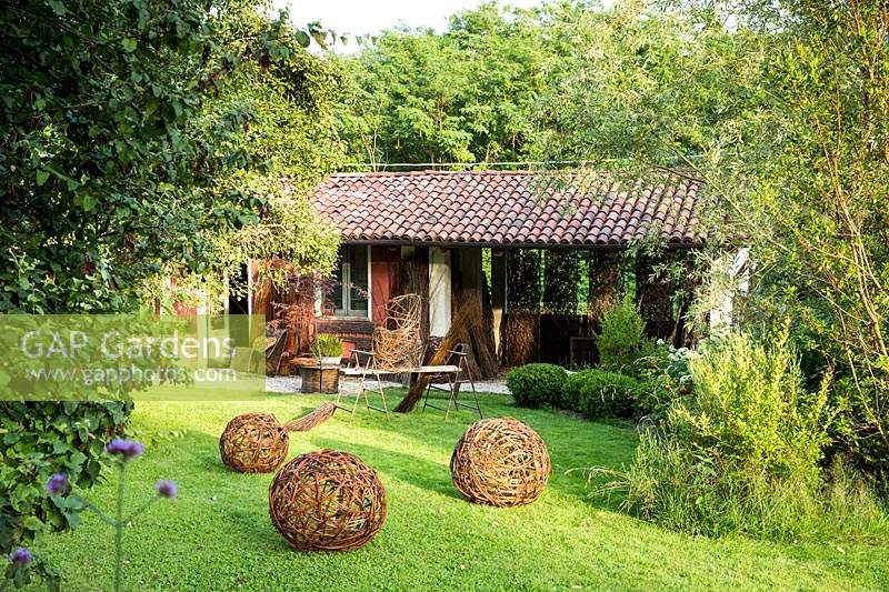 View across lawn with woven willow spheres to crafter' studio