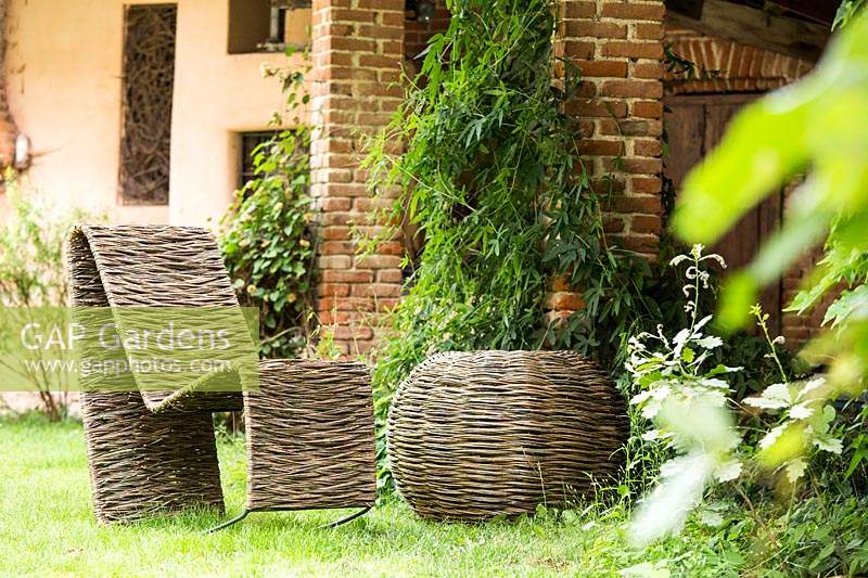 Handcrafted woven Salix - Willow - rocking chair and circular table on grass by building 