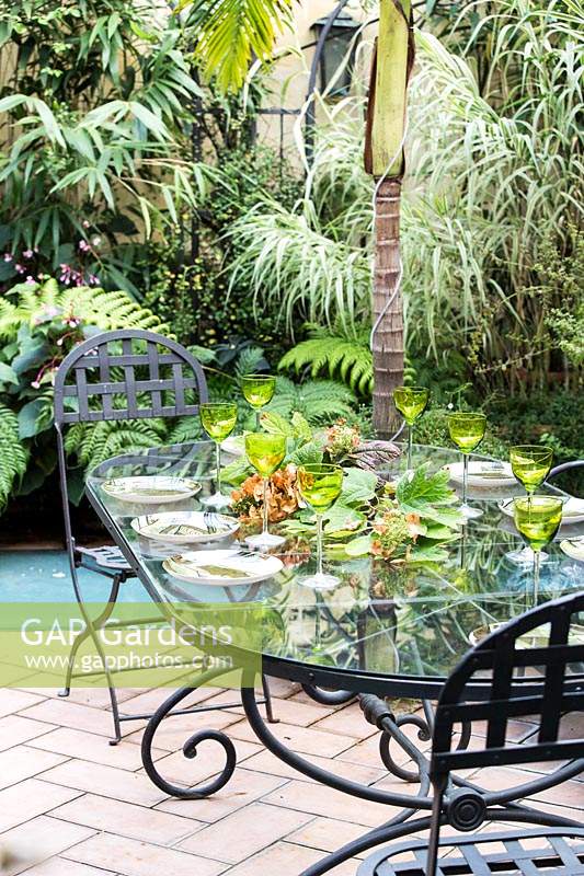 Dining table in garden with tropical planting.