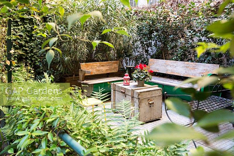 Wooden benches and trunk-table in courtyard garden. 