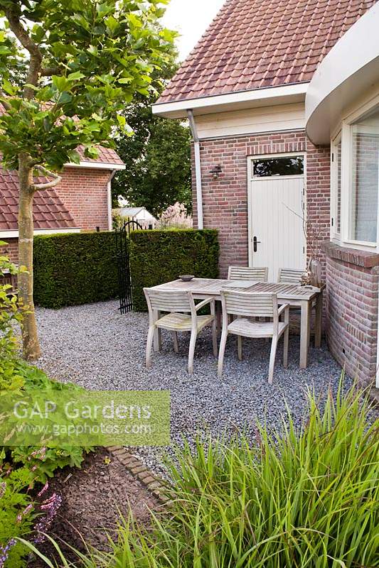 Relaxing area on gravel patio near house, hedge with neighbouring property beyond