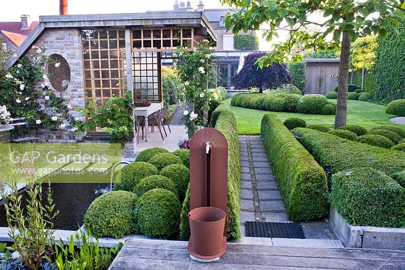Contemporary garden with pond, water feature and box topiary.
