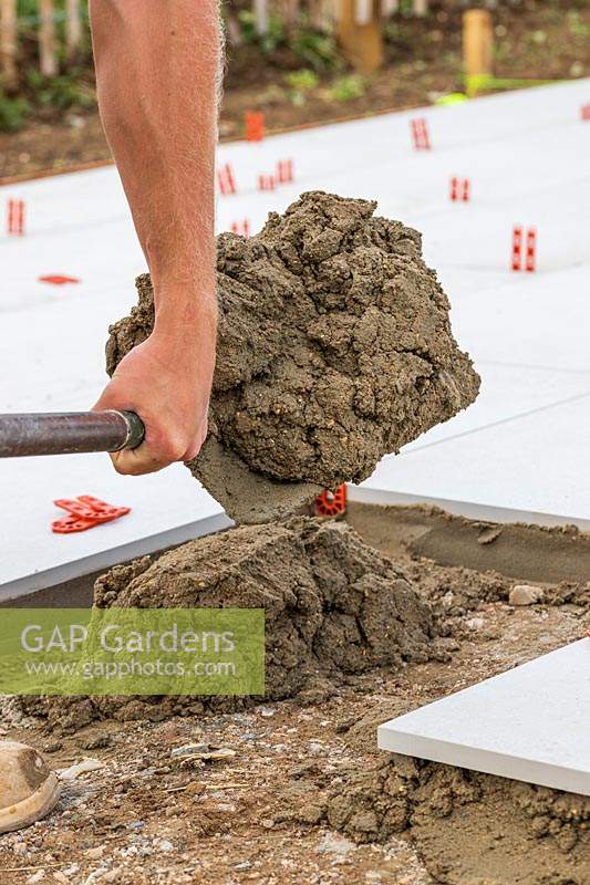 Man with shovel of mixed cement for a patio base