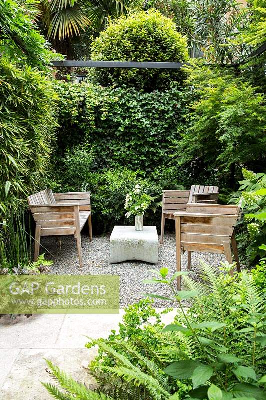 A private corner of the garden with seating screened by Phyllostachys bissetii - Bamboo, Hedera hibernica - Ivy and Hydrangea quercifolia 'Pee Wee'