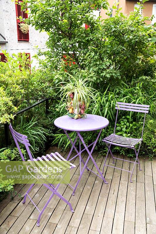 A first floor terrace with deck, seating and a foliage screen of Malus 'Evereste' - Crabapple Tree plus shrubs either side of metal rail