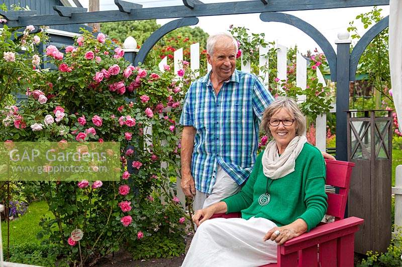 Couple in a Rosa - Rose - garden with wooden painted objects 