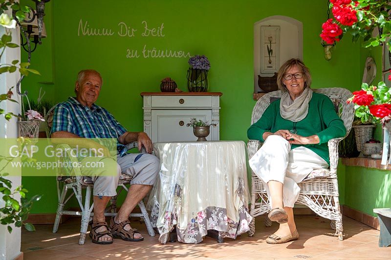 Couple sitting in a garden room with painted wall and decorated with ornaments