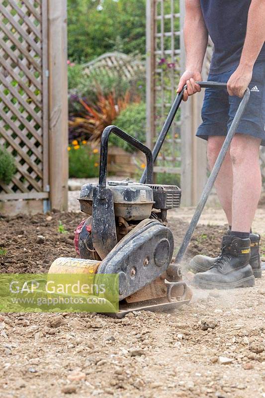 Man using wacker plate to compact base for laying patio
