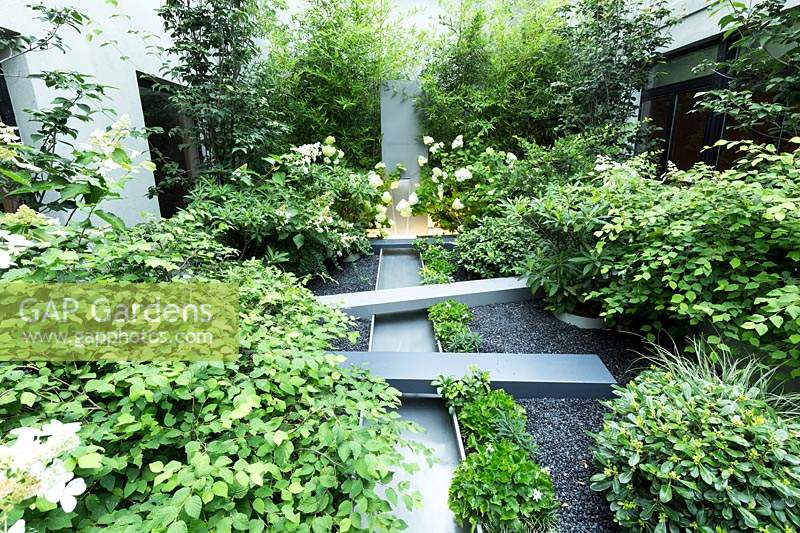 Mixed planting surrounding a metal water feature 