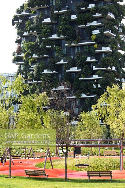 Public park with young trees, benches and playground, in background Bosco Verticale - Vertical Forest - by architect Stefano Boeri 