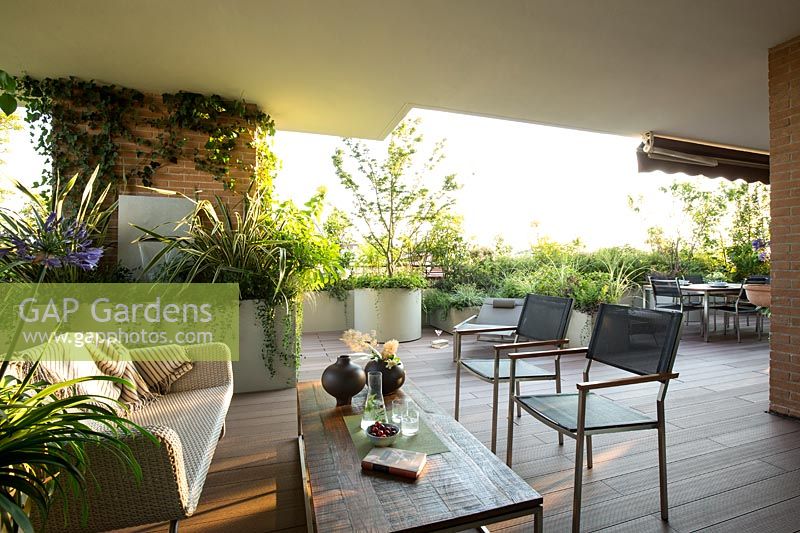 Overview of terrace with the living undercover out to open with more seating and container plantings providing a screen