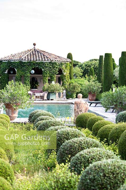 Mixed topiary beside the swimming pool with figurative sculpture. The garden focuses on perfumed evergreens