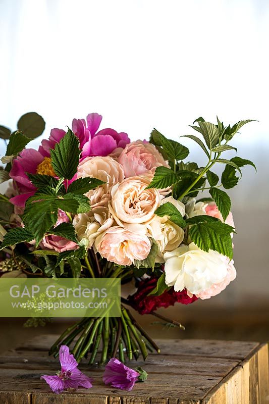 Handtied bunch of Rosa - Rose - and Paeonia - Peony - on wood