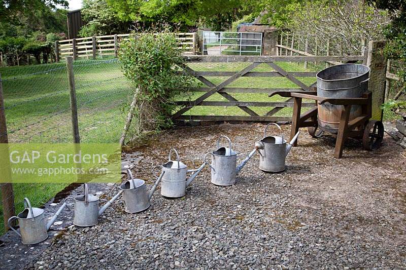 Watering cans arranged in height order near old water tank 
