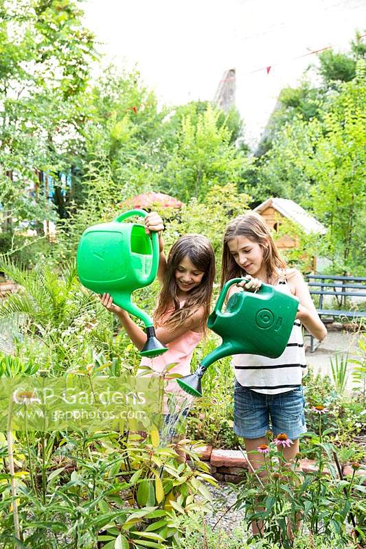 Girls watering plants in a community garden 