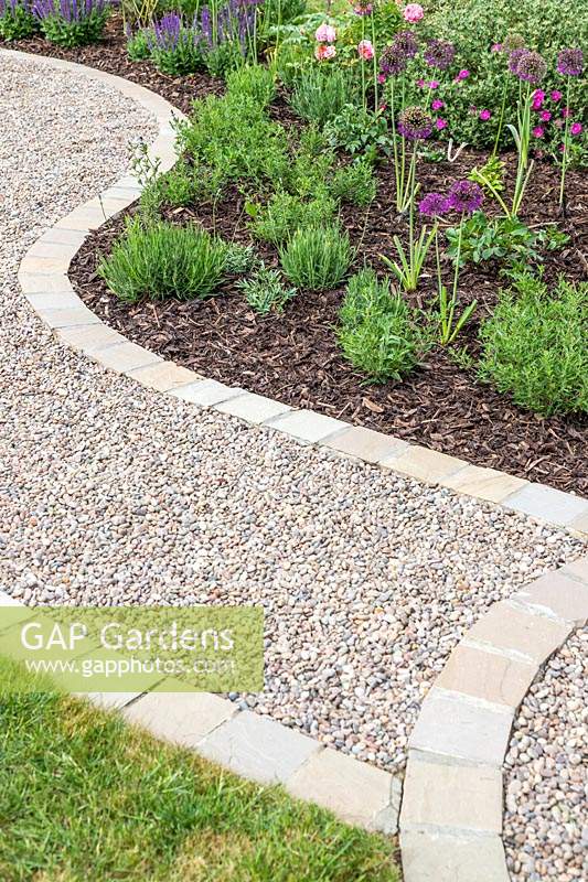 Curved gravel garden path with with 'Scottish Pebbles' gravel and edged with sandstone setts in 'Castle Grey'