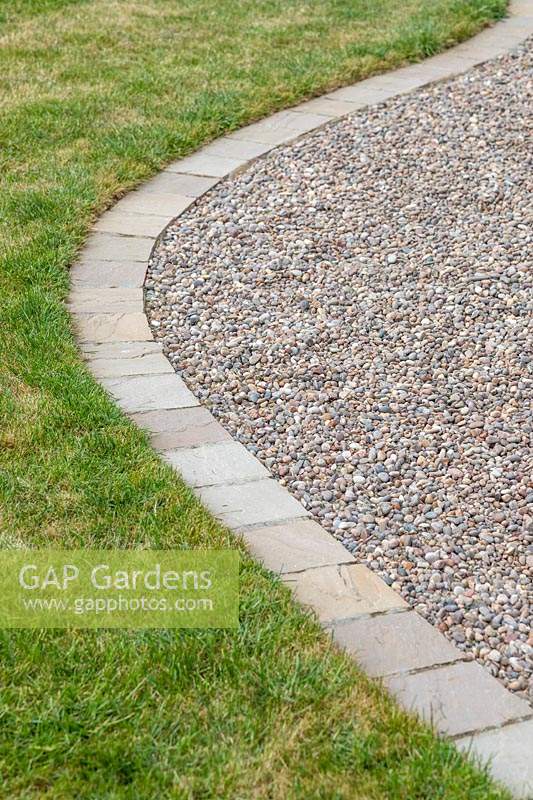 Curved gravel garden path with with 'Scottish Pebbles' gravel and edged with sandstone setts in 'Castle Grey' against a lawn 
