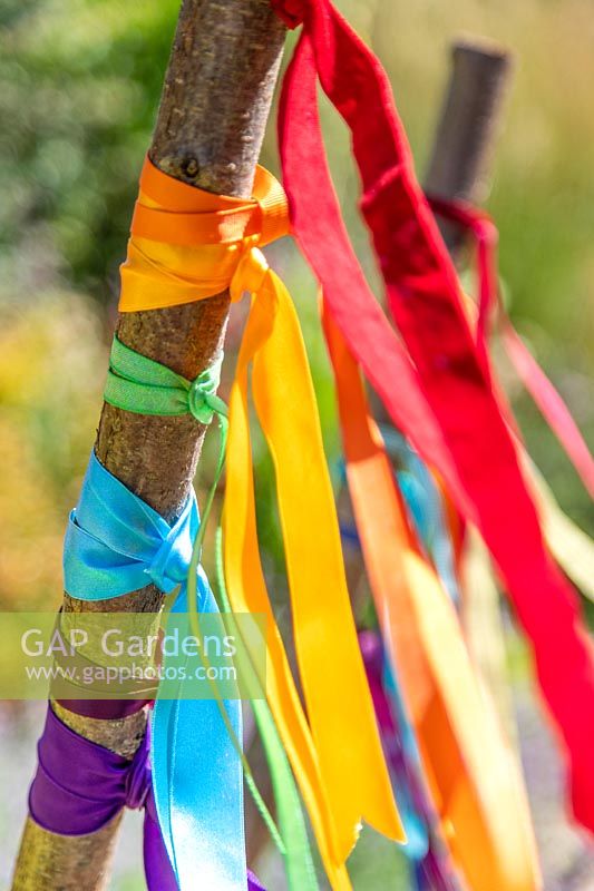 Close up detail of ribbons in the colour of the rainbow tied to hazel poles