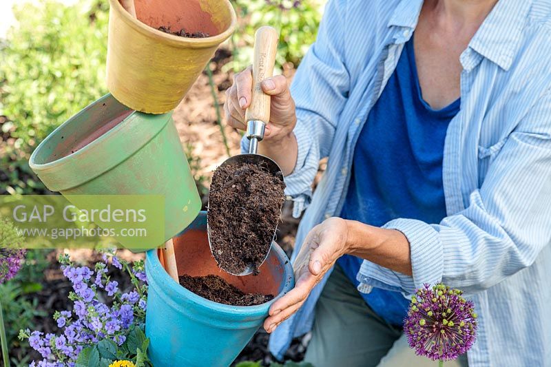 Woman adding compost to rainbow pot tower