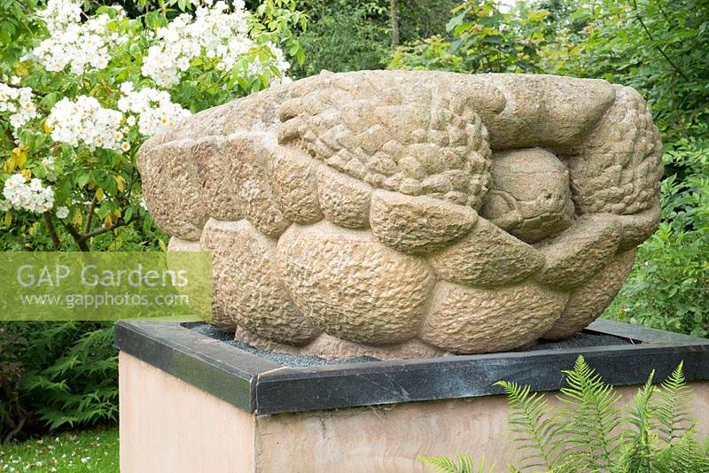 Stone turtle sculpture on a plinth set in a garden