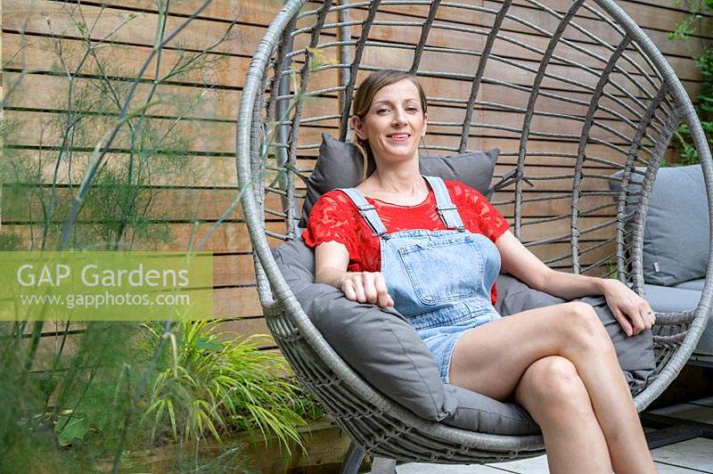 Owner of modern courtyard garden sitting in her hanging chair