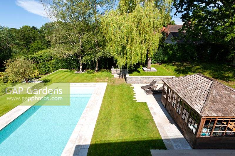Modern tiered garden with swimming pool and summer house, set in lawn with hard landscaped details
