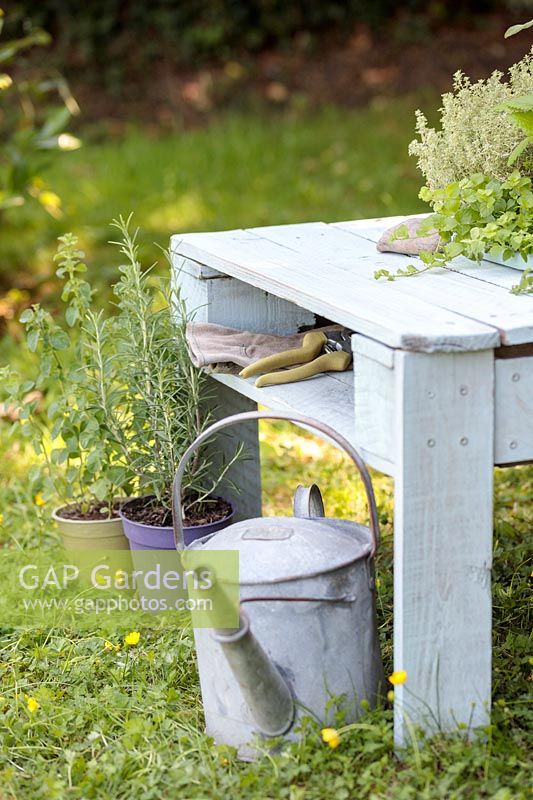 Close up detail of pallet table with central shelf for storing a pair of secateurs and gloves. 