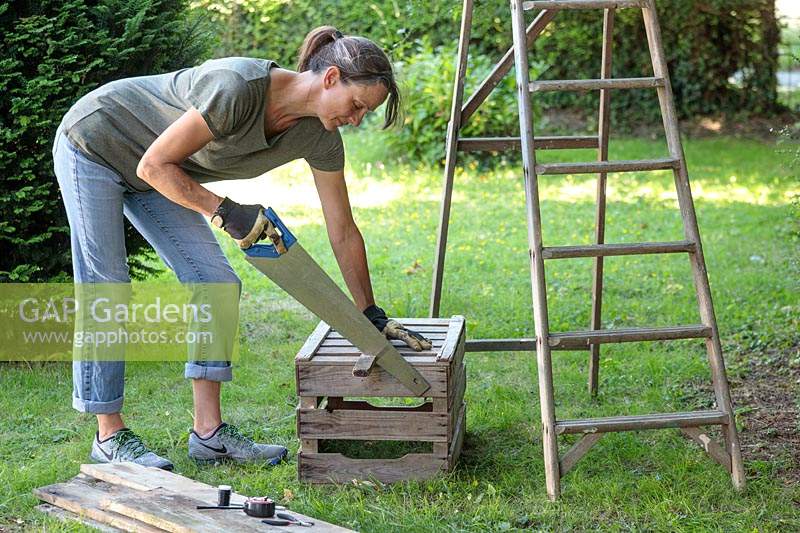 Woman sawing wooden strip to fit to wooden ladder unit