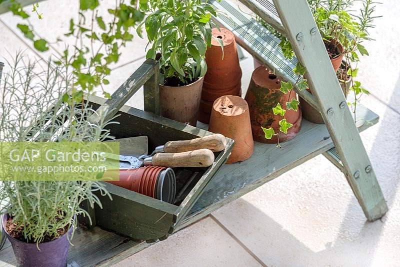 Detail of wooden shelving ladder unit with potted plants and tools