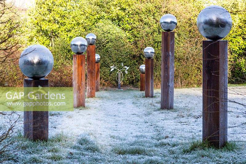 The Meadow with frosted grass and avenue of wood columns with frosted stainless steel globes. Winter