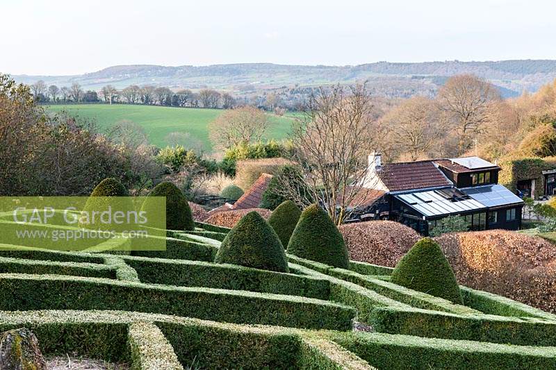 Sloping formal country garden with views of countryside beyond. April. 