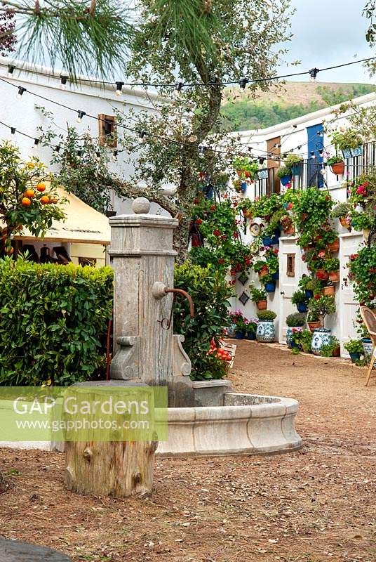 Spanish village square with drinking fountain and wall mounted pots of Geraniums - RHS Malvern Spring Festival