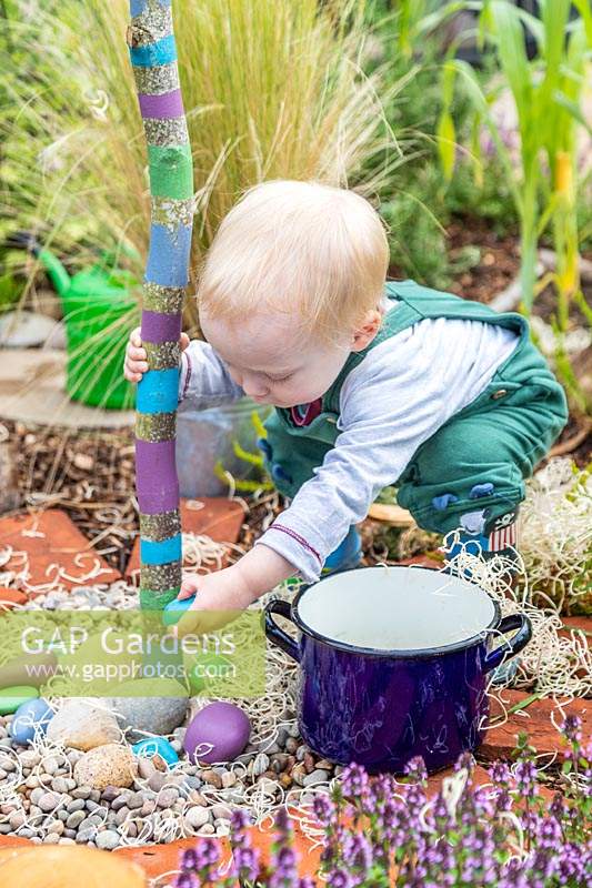 Young toddler playing with stones in sensory garden
