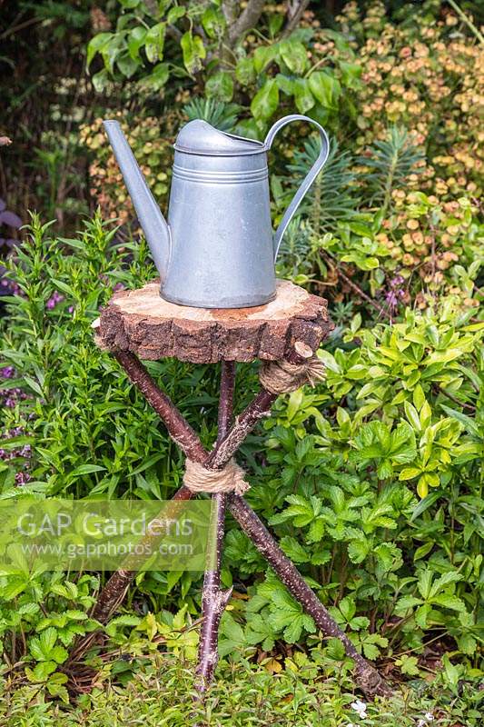 Watering can sitting on tripod table