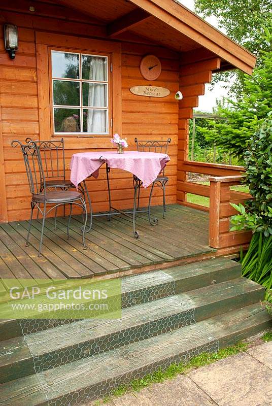 Table and chairs on verandah of summerhouse with wooden steps and wire netting fixed to them for safety - Open Gardens Day, Kelsale, Suffolk