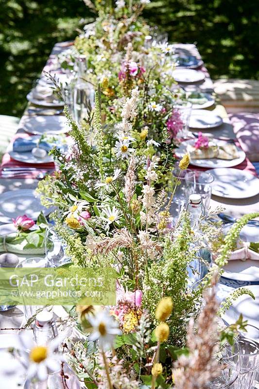Summer table setting in orchard with central floral arrangement 