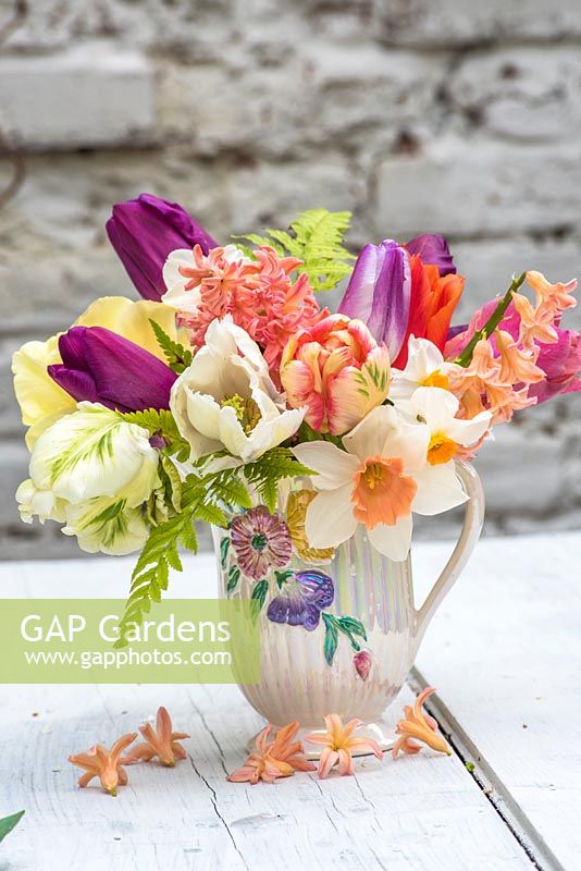 Mixed spring bouquet in vintage jug with tulips, hyacinths, ferns and narcissus
